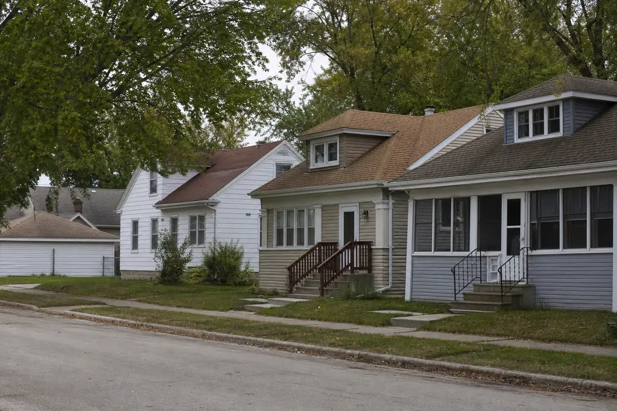 A quiet block of older working-class homes with mature trees and detached garages — about cash home buyers — Cudahy, WI