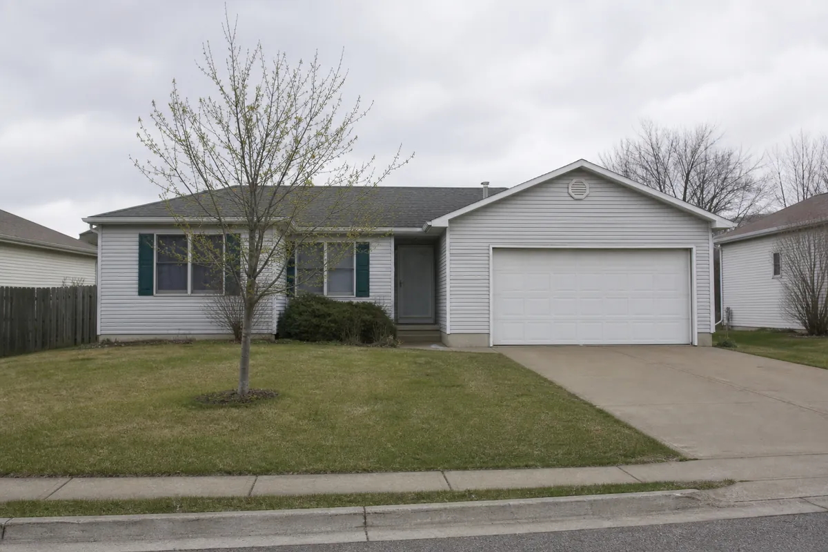 An early-1990s subdivision house with an attached garage and a young front tree — we buy houses oak creek — Cudahy, WI