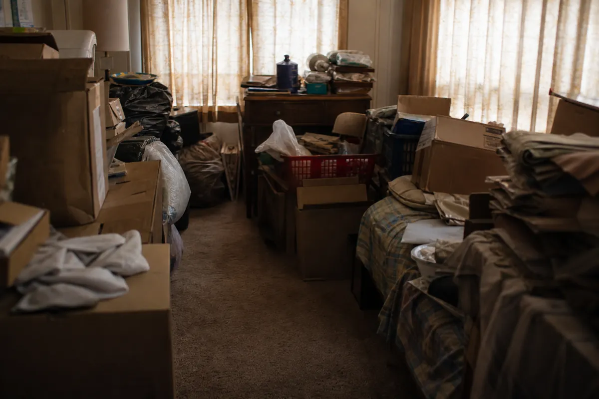 A residential room densely filled with stacked boxes, bags and household belongings — sell hoarder house — Cudahy, WI